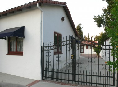 Side of house and long driveway (with small RV/boat parking) complemented by handsome wrought iron gate.