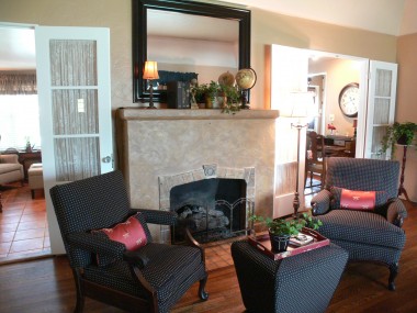 Unique gas and wood-burning fireplace with tall mantle, flanked by French doors leading to family room.
