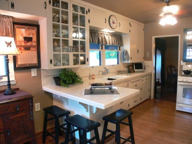 Bright and lovely updated kitchen with glass cabinets, tile counter tops and gas stove.