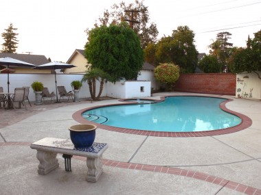 View of low-maintenance backyard with flagstone patio area for table, umbrella and chairs.
