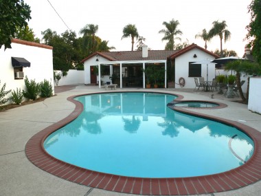 View of back of house with guest quarters to the left and pool equipment behind privacy block wall to the right.